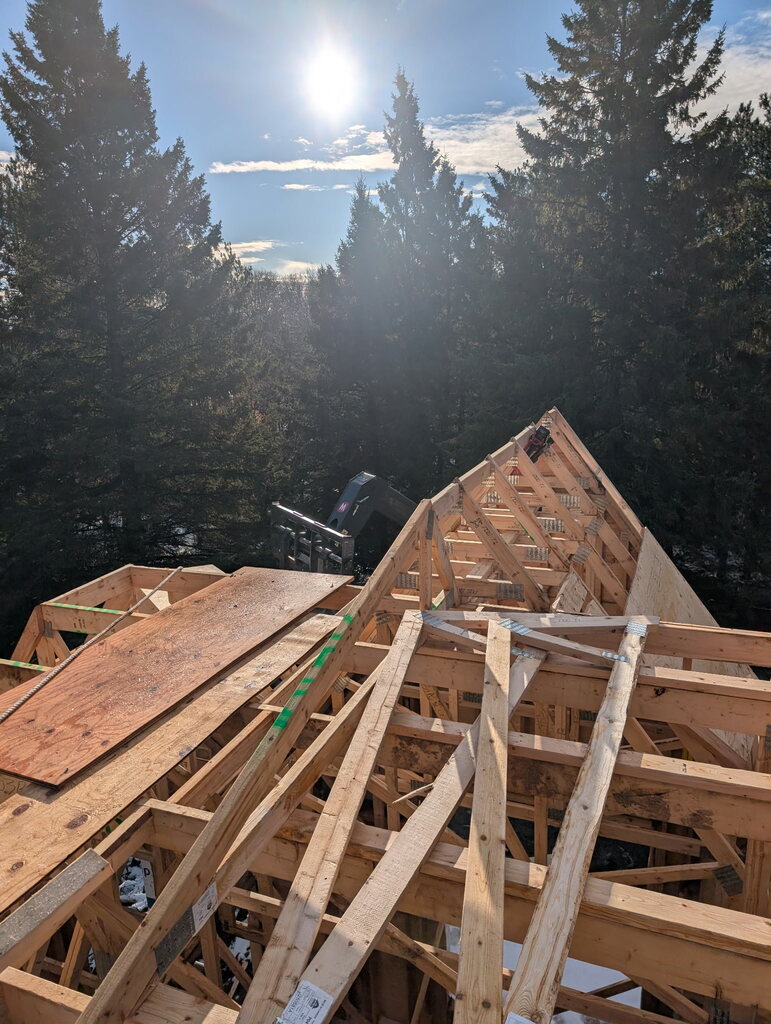A worker stands on top of a roof, prepping for the day's labour