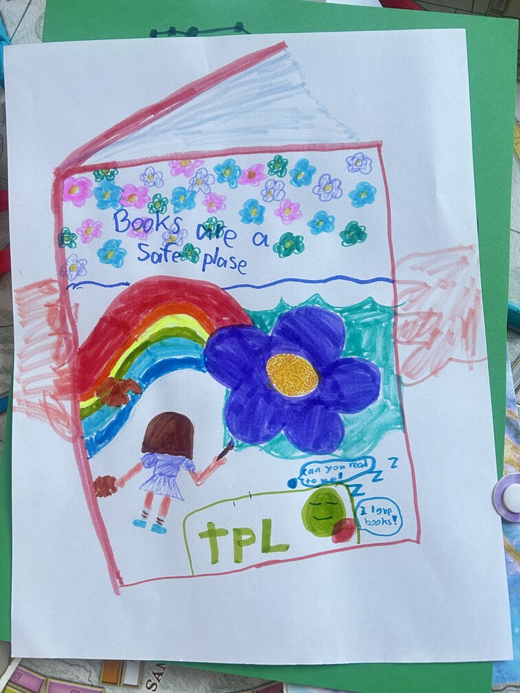 two hands are holding a book and one the cover a little girl is painting